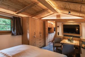 a bedroom with a bed and a desk and a tv at Bärenbach - Almhütte Saalbach in Saalbach Hinterglemm