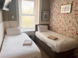 two beds in a small room with a window at The Boho - 4 min walk to beach & town in Bournemouth