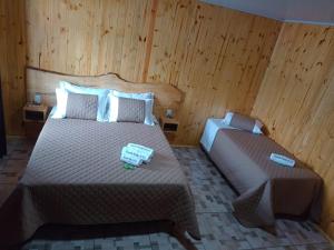 Un dormitorio con dos camas en una habitación con paredes de madera. en Pousada Refúgio do Sol, en Cambará