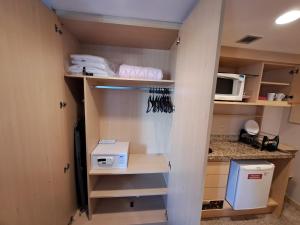 um quarto com uma cozinha com prateleiras e um micro-ondas em Flat particular no Lets Idea Brasília em Brasília