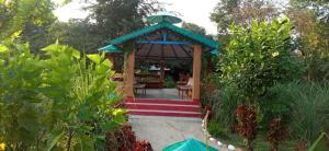 Corbett Nature Retreat في رامناجار: شرفة مع طاولة وكراسي في حديقة