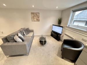a living room with a couch and a television at Fantastic convenient 2 Bedroom 2 bathroom Perfect for Stansted Airport, 3 minute walk to Bishops Stortford Train Station! in Bishops Stortford