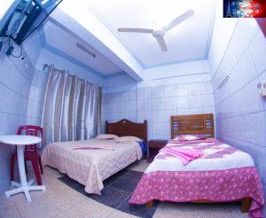 a bedroom with two beds and a table and a ceiling at RESIDENCIAL FRANCIA in Santa Cruz de la Sierra