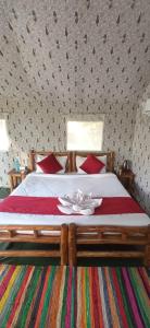 a bedroom with a large bed with red pillows at Corbett Nature Retreat in Rāmnagar