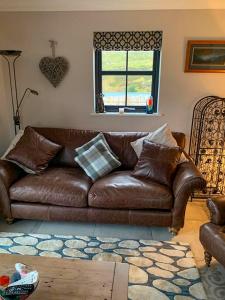 un divano in pelle marrone in soggiorno di Old Manse Cottage a Durness