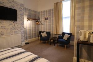 a hotel room with a bed and two chairs and a television at The Raincliffe Hotel in Scarborough