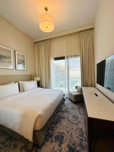 a hotel room with a large bed and a large window at Ocean Mountain View Apartment at The Address Fujairah in Fujairah