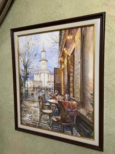 a painting of a table and chairs on a wall at Fontush Boutique Hotel in Ivano-Frankivsk