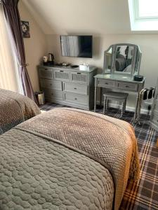 a bedroom with a bed and a dresser with a mirror at Old Manse Cottage in Durness +9 photos