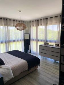 een slaapkamer met een bed, een dressoir en ramen bij Villa de 4 chambres avec piscine privee jardin clos et wifi a Deyme in Deyme