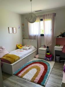 een kinderkamer met een bed met een regenboog tapijt bij Villa de 4 chambres avec piscine privee jardin clos et wifi a Deyme in Deyme