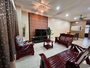 een woonkamer met houten meubels en een televisie bij Grand Homestay Kulim 4-Bedroom in Lunas