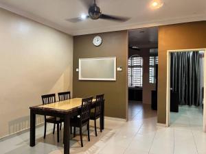 a dining room with a table and chairs and a clock at Grand Homestay Kulim 4-Bedroom in Lunas