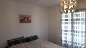 een slaapkamer met een bed en een kroonluchter bij Le Charleston 3p 5 minutes Disney Parking gratuit Terrasse in Chessy