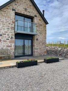 a brick house with two flower beds in front of it at Old Manse Cottage in Durness