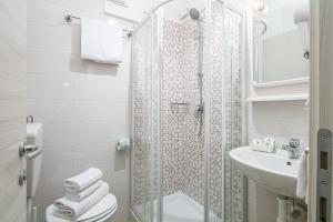 a bathroom with a shower and a toilet and a sink at Hotel Pigalle in Lido di Jesolo