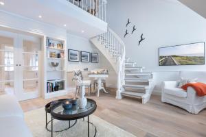 ein weißes Wohnzimmer mit einer Treppe und einem Tisch in der Unterkunft Ferienwohnung Luettje Moehl - Kleines Paradies am Wattenmeer in Keitum Sylt in Keitum
