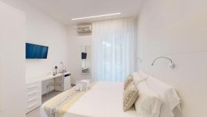 una camera bianca con letto e lavandino di Hotel Ligure a Spotorno