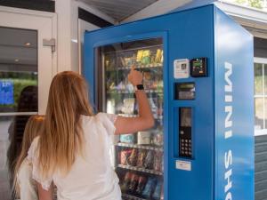 a woman is standing in front of a vending machine at TopParken – Recreatiepark de Wielerbaan in Wageningen