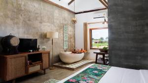 a bedroom with a tub and a bed and a television at Dontrei Villa Angkor in Siem Reap