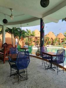 eine Terrasse mit Tischen und Stühlen und einem Pool in der Unterkunft Wayahnb'al eco hostal in Acapulco