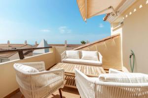 einen Balkon mit weißen Stühlen, einem Tisch und einem Sofa in der Unterkunft Bright Nordic style penthouse in beachside resort in Marbella