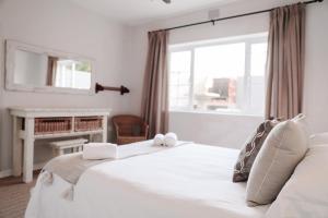 a bedroom with a large white bed with a window at Amblewood Beach Cottages in Kenton on Sea