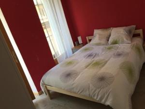 1 cama en un dormitorio con una pared roja en Le Cocon, en Luchon 4 fotos más