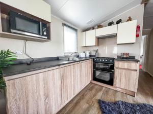 a kitchen with wooden cabinets and a black counter top at Lovely 6 Berth Caravan At Seaview Holiday Park In Kent Ref 47001d in Whitstable