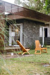 two wooden chairs sitting in front of a house at Descanso en La Caleta in Mar de Cobo