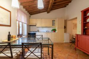 Villa La Tinaia Il Sole Verde في Bucine: مطبخ مع طاولة وكراسي زجاجية