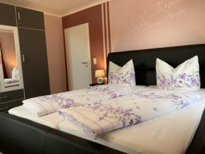 a large bed with purple and white sheets and pillows at Ferienhaus SweetDreams in Bad Sachsa