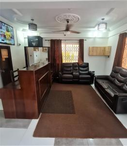 a living room with black leather furniture and a kitchen at Bassi Hotel in Sekondi-Takoradi