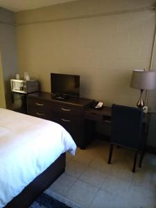 1 dormitorio con 1 cama y escritorio con TV en Park Lane Motor Hotel Medicine Hat, en Medicine Hat