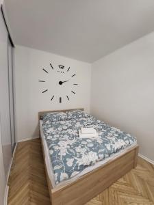 Cama en habitación con reloj en la pared en Apartament przy Lipowej en Białystok