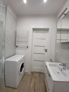 a white bathroom with a washing machine and a sink at Apartament przy Lipowej in Białystok