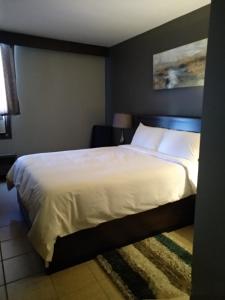 メディシンハットにあるPark Lane Motor Hotel Medicine Hatのベッドルーム1室(大型ベッド1台、白いシーツ、枕付)