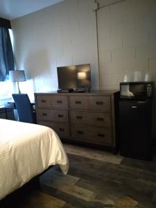 1 dormitorio con 1 cama y vestidor con TV en Park Lane Motor Hotel Medicine Hat en Medicine Hat