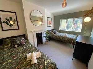 a bedroom with two beds and a mirror at Tipsy Cottage & Games Cabin with fire-pit and BBQ in Ringwood
