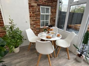 a table and chairs on a porch with food on it at Tipsy Cottage & Games Cabin with fire-pit and BBQ in Ringwood