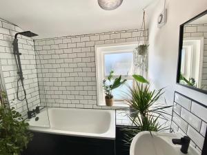 a bathroom with a white tub and plants in it at Tipsy Cottage & Games Cabin with fire-pit and BBQ in Ringwood