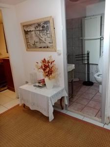 een badkamer met een tafel met een vaas met bloemen erop bij Au Calme in Verneuil d’Avre et d’Iton
