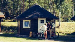 a man and a woman standing in front of a small shed at Troll Camping in Evje