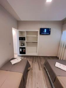 a room with two beds and a tv on the wall at Hotel TOTEM Boutique in Termas de Río Hondo