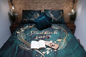a bed with a bedspread with a book and a glass of wine at Loft Parkowa in Przemyśl