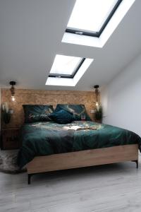 a bedroom with a bed with green sheets and skylights at Loft Parkowa in Przemyśl