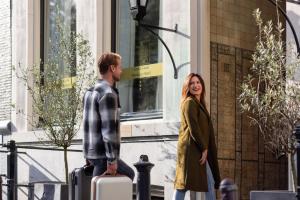 un homme et une femme debout à l'extérieur d'un bâtiment avec bagages dans l'établissement Grand Canal Boutique Hotel, à Amsterdam