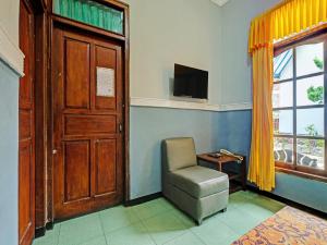 a room with a chair and a door and a television at SPOT ON 91912 Hotel Citra Dewi 2 in Semarang