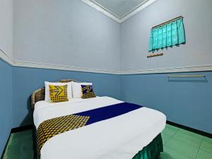 a bedroom with a bed with blue walls and a window at SPOT ON 91912 Hotel Citra Dewi 2 in Semarang