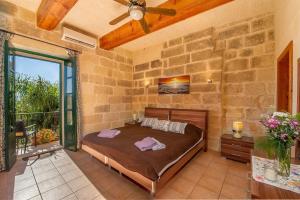 - une chambre avec un lit et un mur en pierre dans l'établissement Razzett Tuta Holiday Home, à Kerċem